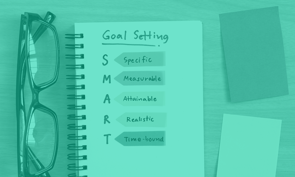 A notebook open on a page titled 'Goal Setting' and SMART goals written down underneath.